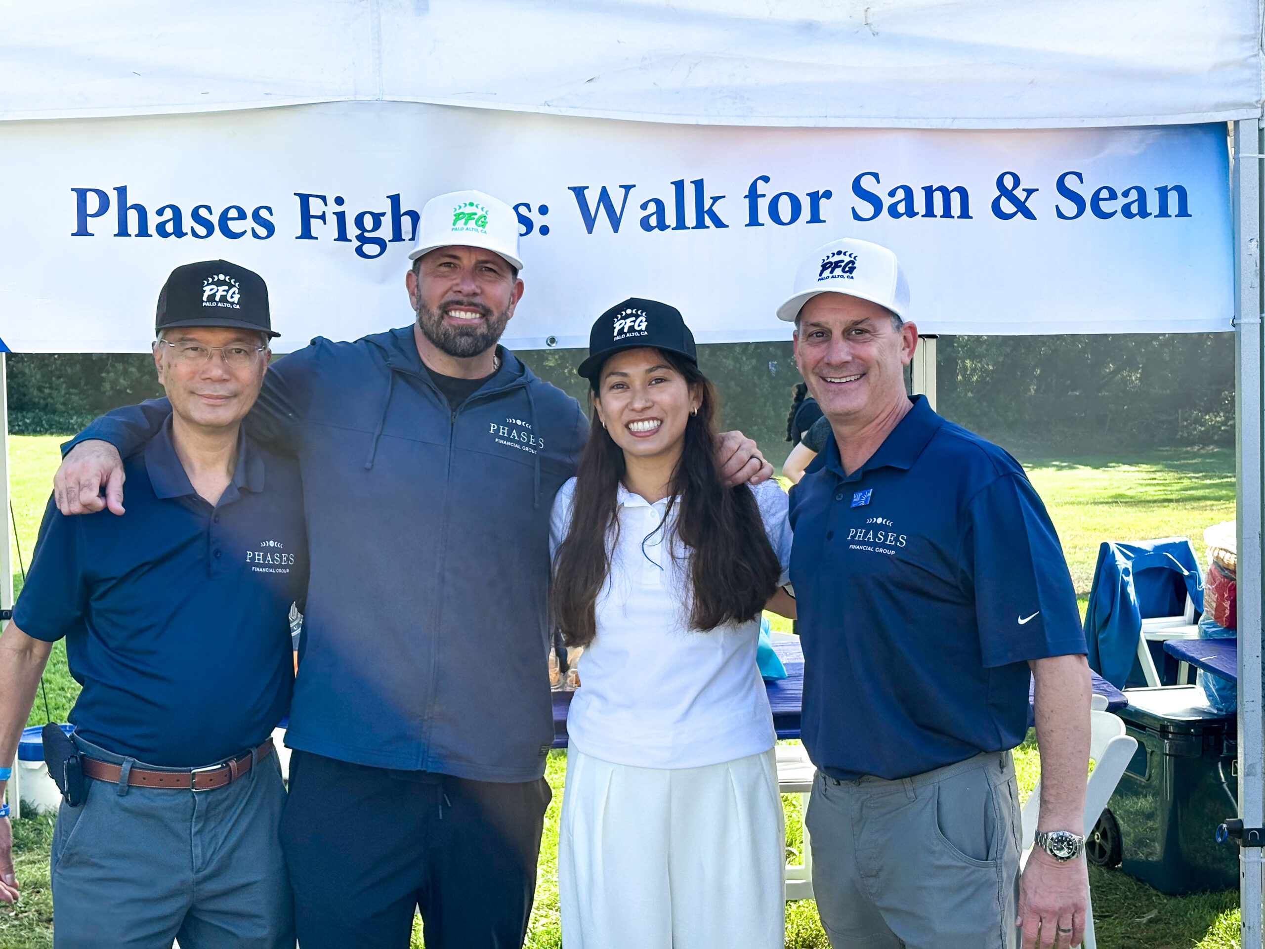 Phases Financial Group team members wearing branded caps pose together at the Breakthrough T1D Walk under the Phases Fighters banner.