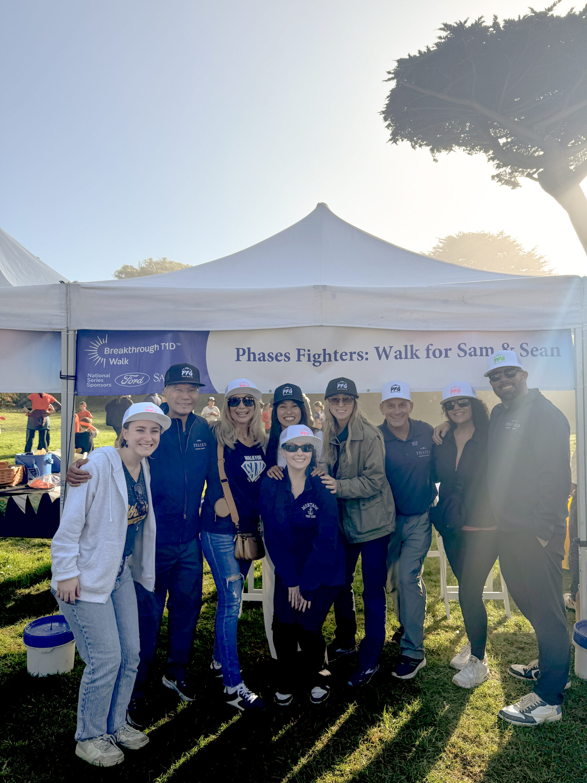 A larger group of Phases Financial Group supporters pose together under the Phases Fighters banner at the Breakthrough T1D Walk.