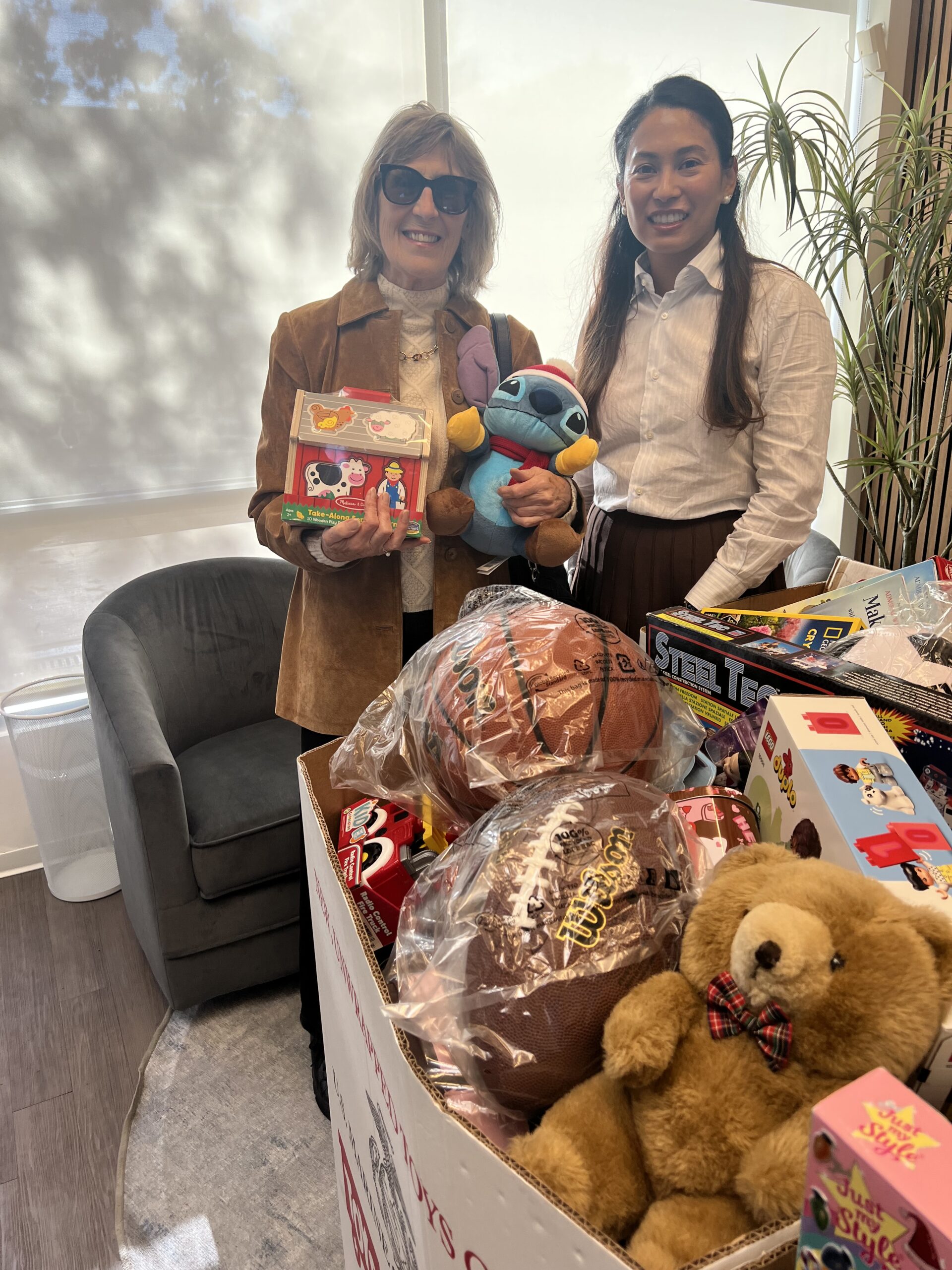 Two clients hold stuffed animals and toys donated for Phases Financial Group's Toys for Tots drive.