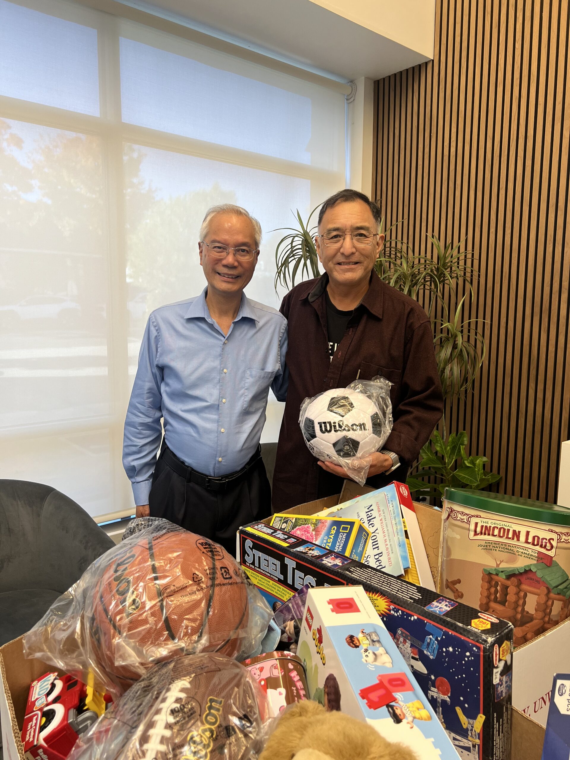 Two clients hold a soccer ball and other donated toys for Phases Financial Group's Toys for Tots drive.