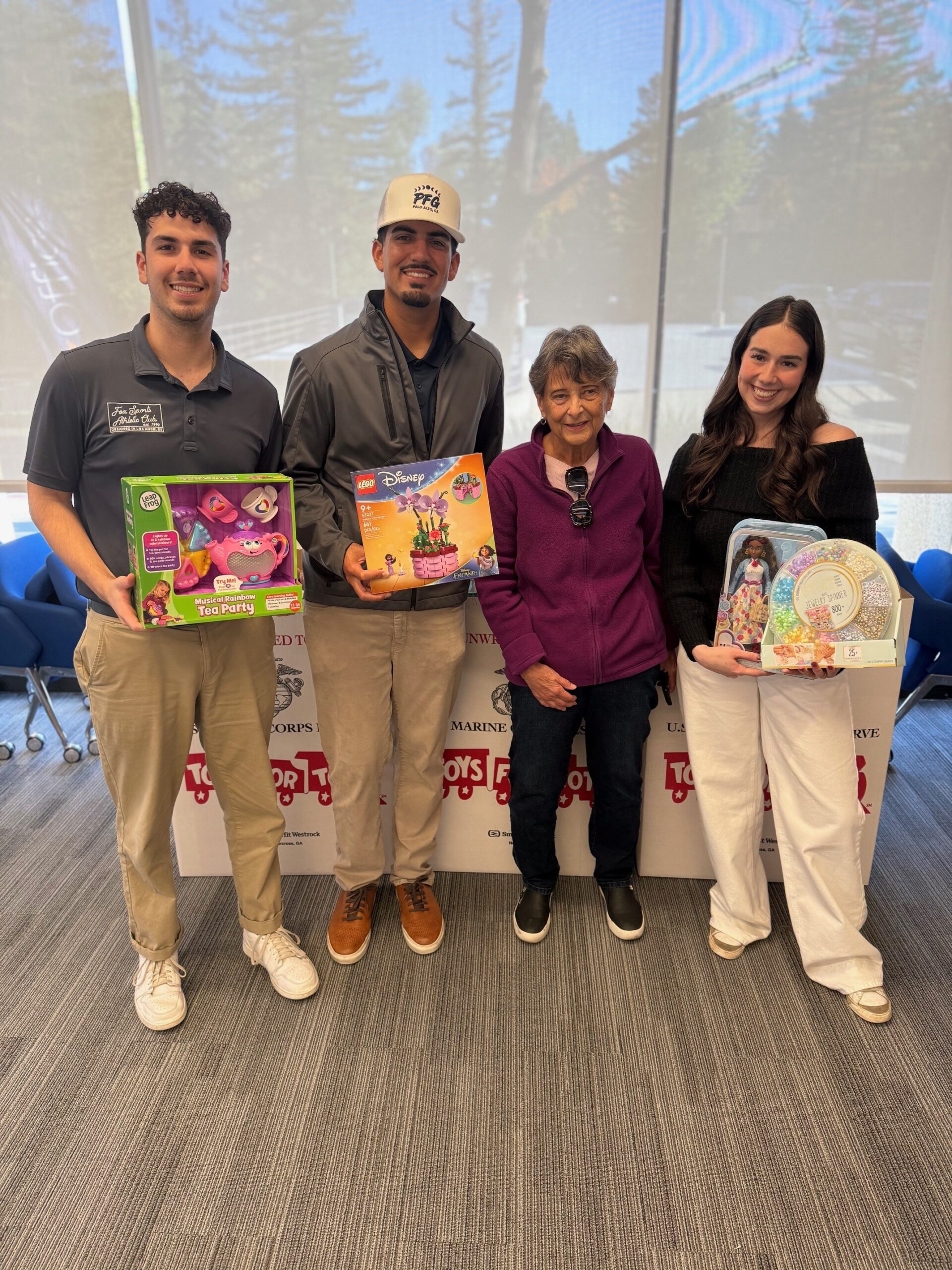 Carol MacDonell and family hold toys donated for Phases Financial Group's Toys for Tots drive, joined by two Phases Financial Group team members.