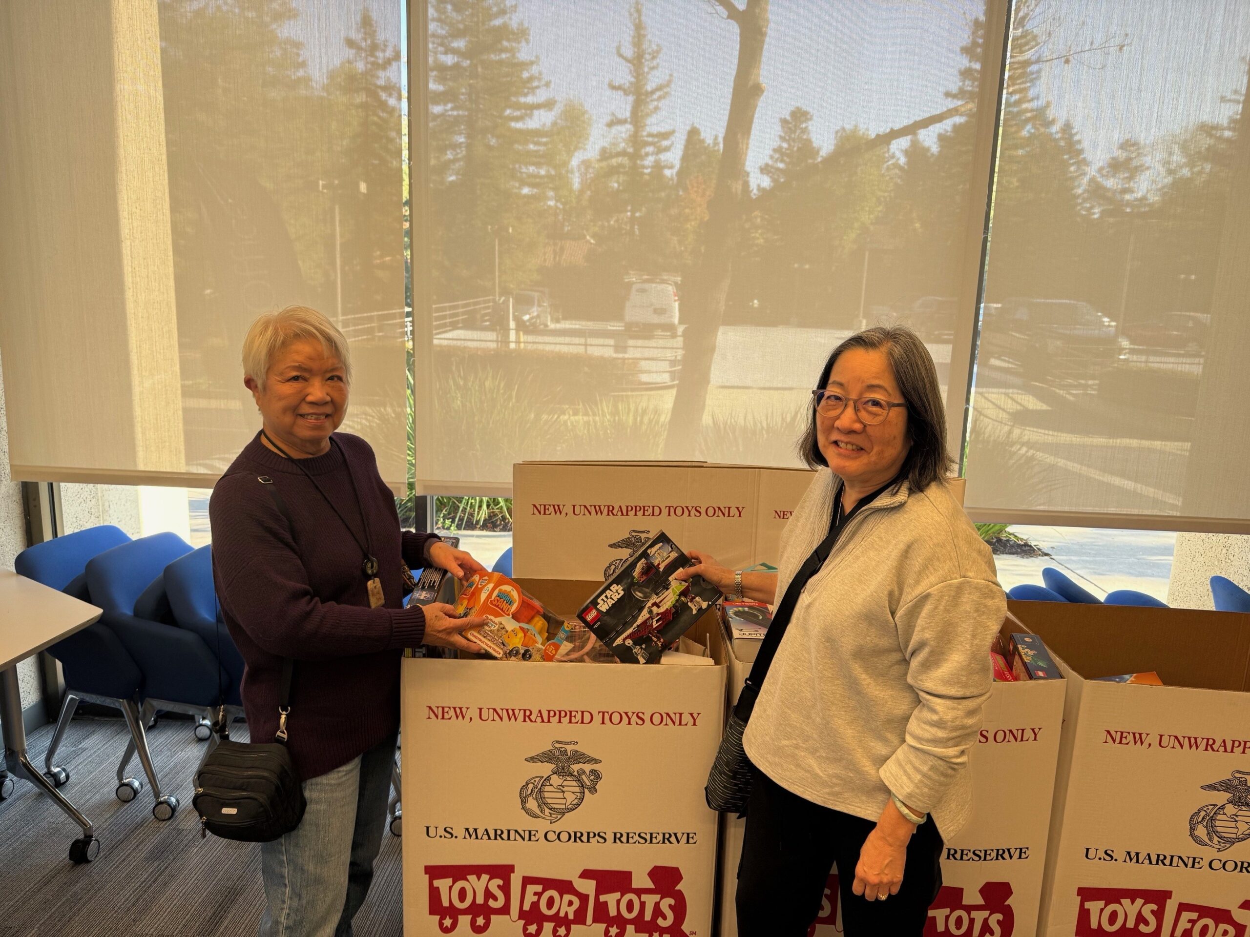 Fran Low and Karen Oka pack donated toys into a Toys for Tots collection box at Phases Financial Group's office.