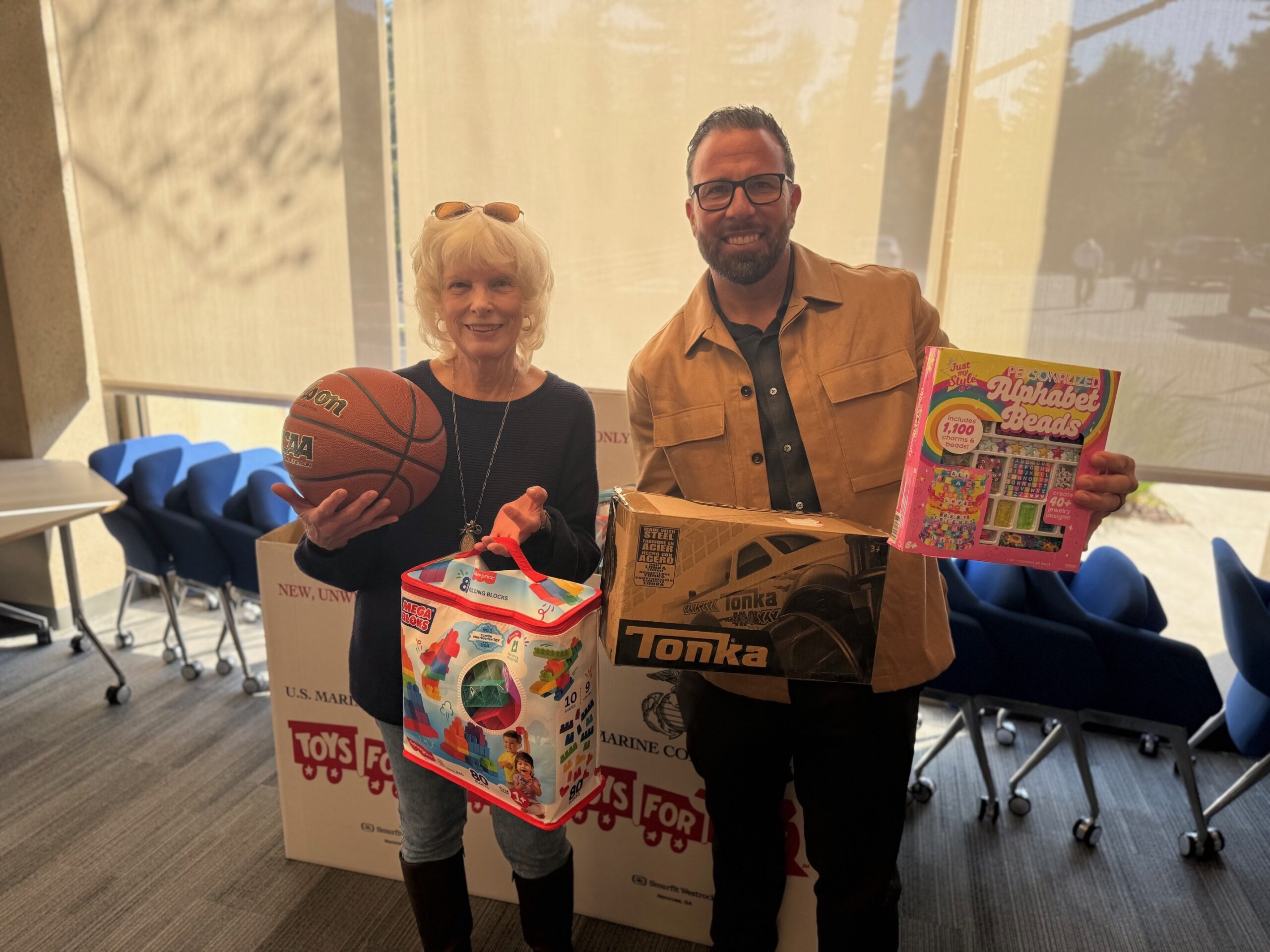 Gloria Courtney and a companion hold donated toys, including a basketball, for Phases Financial Group's Toys for Tots drive.