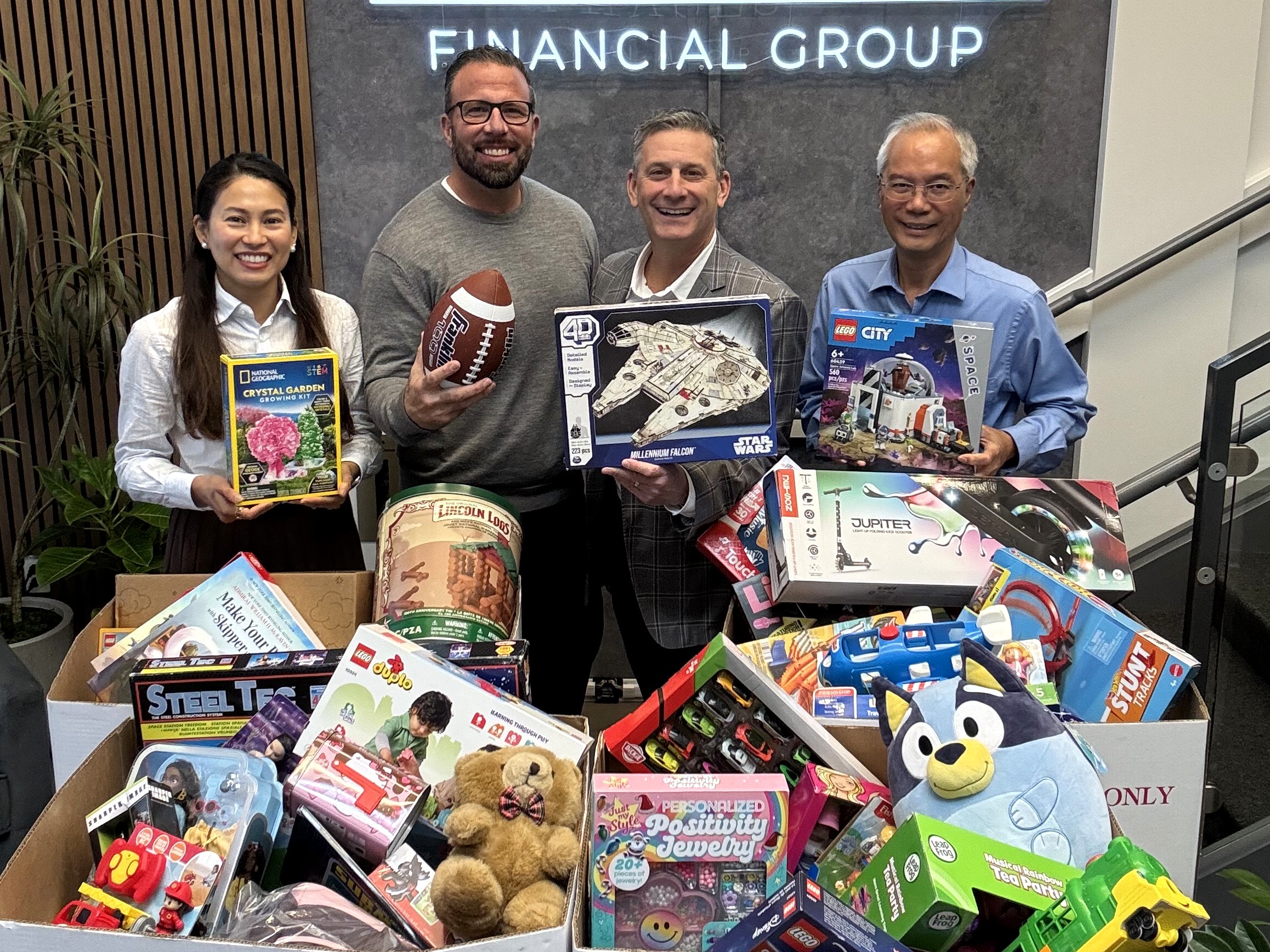 Clients and team members of Phases Financial Group hold toys donated for the firm's Toys for Tots charity drive.