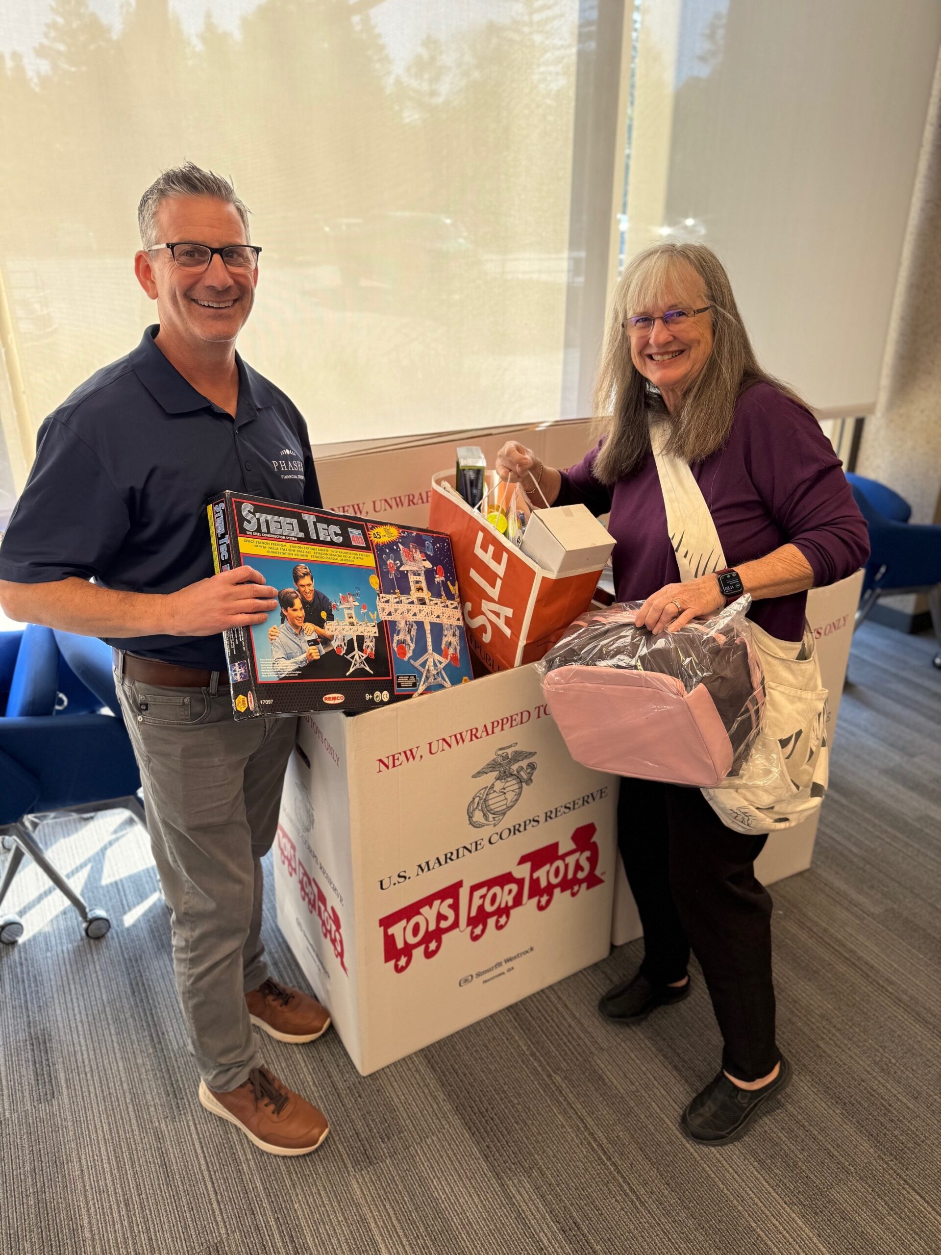 Karen Weigel and a Phases Financial Group team member hold toys donated for the firm's Toys for Tots drive.