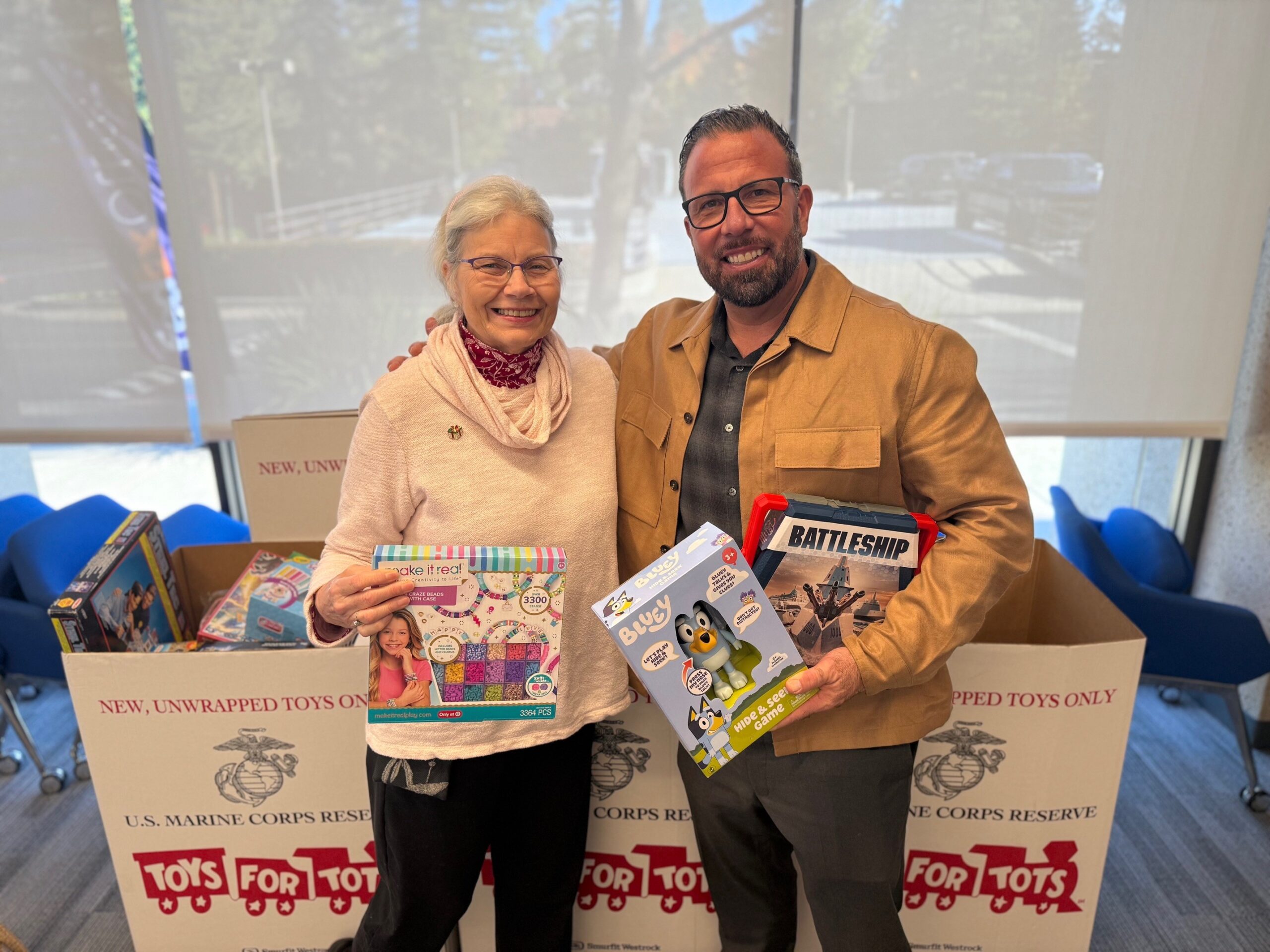 Sarah Nelson and a companion hold board games and toys donated for Phases Financial Group's Toys for Tots drive.