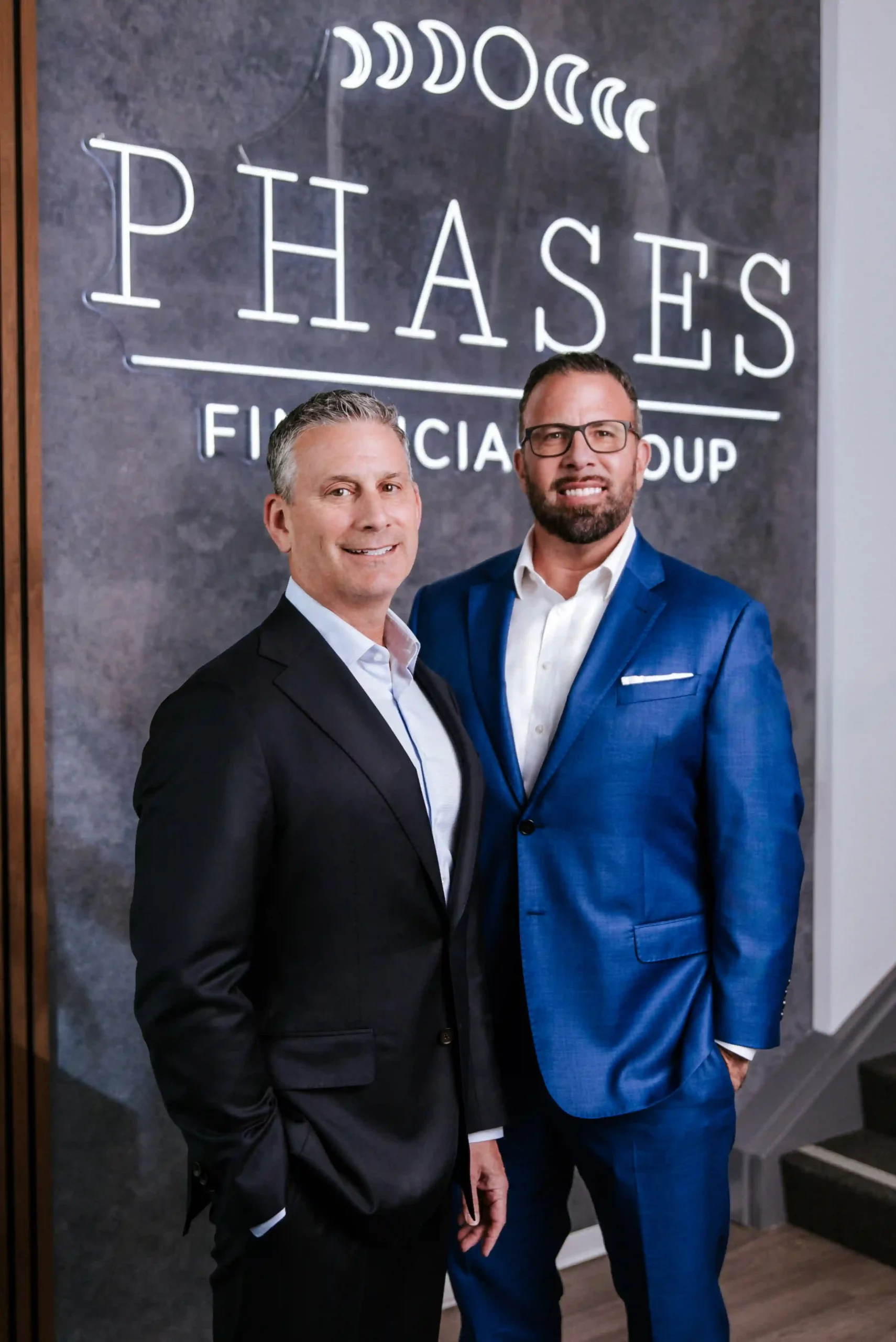 Two Financial Advisors and Partners at Phases Financial Group standing together in front of the firm's sign in their Palo Alto, CA office.